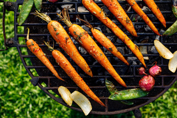 Wall Mural - Grilled carrots in a herbal marinade on a grill plate, outdoor, top view. Grilled vegetarian food, bbq