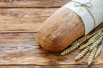 Wall Mural - Loaf of fresh  bread and wheat ears on wooden table