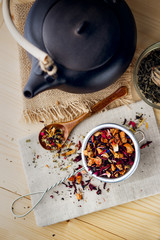 Wall Mural - Black ceramic teapot with tea,Different tea and herbs ,on wooden background.