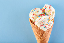 Ice Cream Balls With Colored Sugar Sprinkles In A Waffle Cone On A Blue Background. Vanilla Ice Cream In A Waffle Cone.