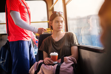 young beautiful woman with glasses on top of her head looking through window and enjoying her coffee