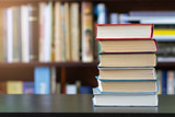 Fototapeta  - A stack of books on the background of bookshelves.