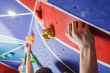 Climber Clings To Climbing Wall With His Hands.