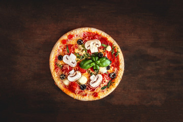 Wall Mural - Fresh Pizza with  mushrooms, tomatoes, cheese and basil leaf  on wooden table closeup. Top view. Pizza Ready to Eat.