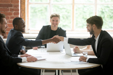 Wall Mural - Smiling african american welcoming on board business partner by handshake at corporate meeting. Company team cheerfully greeting new colleague. Partnership, coworking, cooperation, negotiation concept