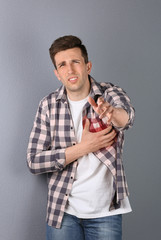 Wall Mural - Young man having heart attack on color background