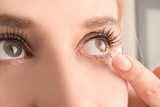 Fototapeta Panele - Young woman putting contact lens in her eye, closeup