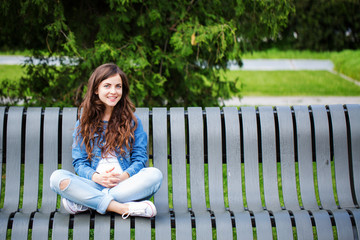 Wall Mural - Beautiful girl student sitting on bench in park.