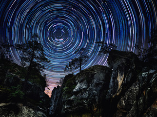 Wall Mural - mountains and trees on starry background with bright stars trails. time lapse, long exposure. elemen