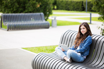 Wall Mural - beautiful girl student sitting on bench in park.