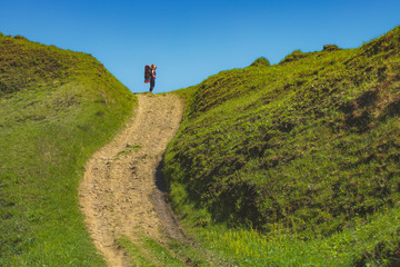 Wall Mural - Girl hiker with backpack against blue sky