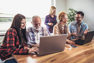 Young volunteers help senior people on the computer. Young people giving senior people introduction to internet