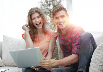 Wall Mural - young couple rejoices,sitting on the couch in front of the open laptop