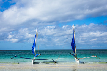 Sailboats moored on a white sand beach