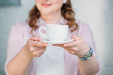  cropped image of woman showing cup of coffee at home