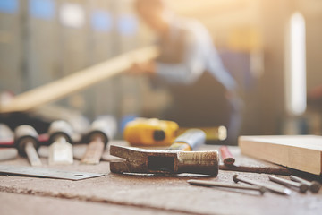 equipment on wooden desk with man working in workshop background. Vintage tone Retro filter effect.