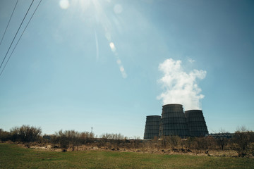 Two big tower of CHPP close-up. White steam from wide pipe of CHP on blue sky. Industrial background image of TPP with copy space. Huge pipes of thermal power plant produce steam for electric power.