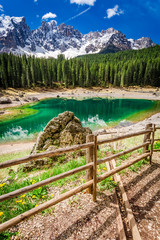 Wall Mural - big rock and green mountain carezza lake in dolomites, italy