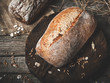 Rustic bread and wheat on an old vintage planked wood table. Dark moody background with free text space.