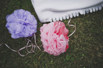 Multicolored pompon balls of paper on the background of green grass at the summer picnic.