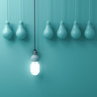 One hanging eco energy saving light bulb glowing and standing out from unlit incandescent bulbs on green pastel wall background , leadership and different creative idea concepts . 3D rendering.