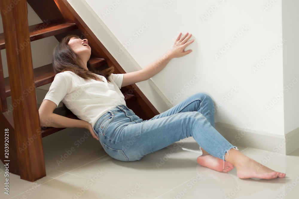 injured woman with hip pain or back injury; portrait of asian woman falling from stair, having pain at her back or hip, concept of pain or injury from accident; 30s adult asian woman model - obrazy, fototapety, plakaty 