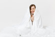 © ViDi Studio - Young brunette woman sitting in bed with white sheet, pillow, wrapping in blanket on white background. Beauty female spending time in room. Rest, relax, good mood concept. Copy space for advertisement