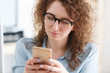 © Rithor - Beautiful young caucasian female student in round glasses reads good news on smart phone, enjoying online communication