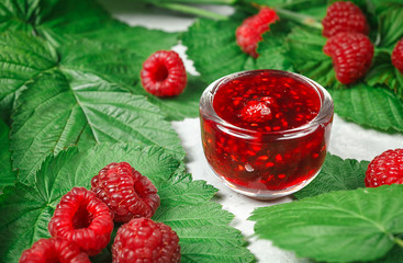 Wall Mural - Red fresh raspberries on white rustic wood background. Bowl with natural ripe organic berries with peduncles and green leaves on wooden table, top view with copy space