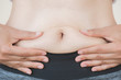 © Siam - woman hand holding her own belly fat. woman diet lifestyle to reduce belly and shape up healthy stomach muscle concept.