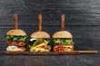 Delicious fresh hamburgers served on wooden plank with knife