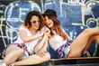 © BalanceFormCreative - Two female teenagers sitting on ramp and hangout at the skate park .Laughing and fun.
