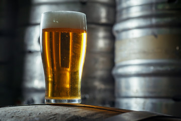 Glass of light beer on a wooden barrel