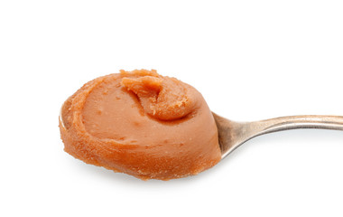 Spoon with delicious caramel on white background