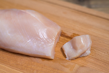 Piece of raw chicken fillet on wooden board ready for cooking