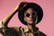 © Carlos David - A fashion portrait of a young woman with purple sunglasses and black hat, isolated on pink studio background
