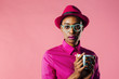 © Carlos David - Portrait of a smart young woman with glasses holding a coffee mug and looking at camera, isolated on pink studio background