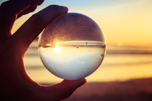 Creative Photography Landscape Concept With Crystal Ball Or Esphere In Hand During Sunset On Beach