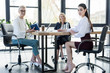 © LIGHTFIELD STUDIOS - three professional businesswomen sitting at table and looking at camera