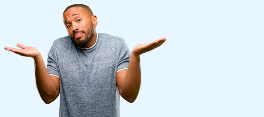 African american man with beard doubt expression, confuse and wonder concept, uncertain future shrugging shoulders isolated over blue background