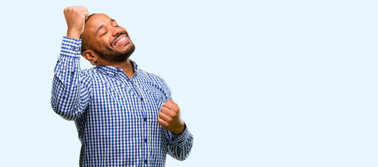 Wall Mural - African american man with beard happy and excited expressing winning gesture. Successful and celebrating victory, triumphant isolated over blue background