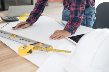 Engineer woman working blueprint at a drawings in office. Engineering tools and construction concept.