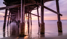 A Warm Autumn Sun Sets Over A California Coast Pier. Memories Of Summer And Play