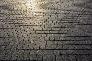 Ancient granite pavement with time-damaged tiles