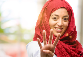 Young arab woman wearing hijab raising his finger, is the number four