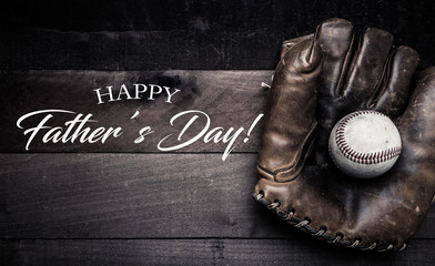 Wall Mural - A group of vintage baseball equipment, bats, gloves, baseballs on wooden background with a father's day greeting