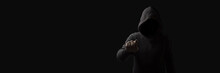 Faceless Man In A Hood With Points A Finger At The Viewer On A Dark Background. Concept Threats And Terror