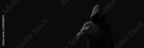 Fotomural Faceless man in a hood with points a finger at the viewer on a dark background