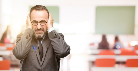 Poster - Teacher man using glasses covering ears ignoring annoying loud noise, plugs ears to avoid hearing sound. Noisy music is a problem. at classroom