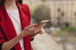 © makarovada - Cropped shot of young girl using modern smartphone device, female hands holding mobile phone on city street, smiling successful female entrepreneur using cellphone wireless connection for work outside
